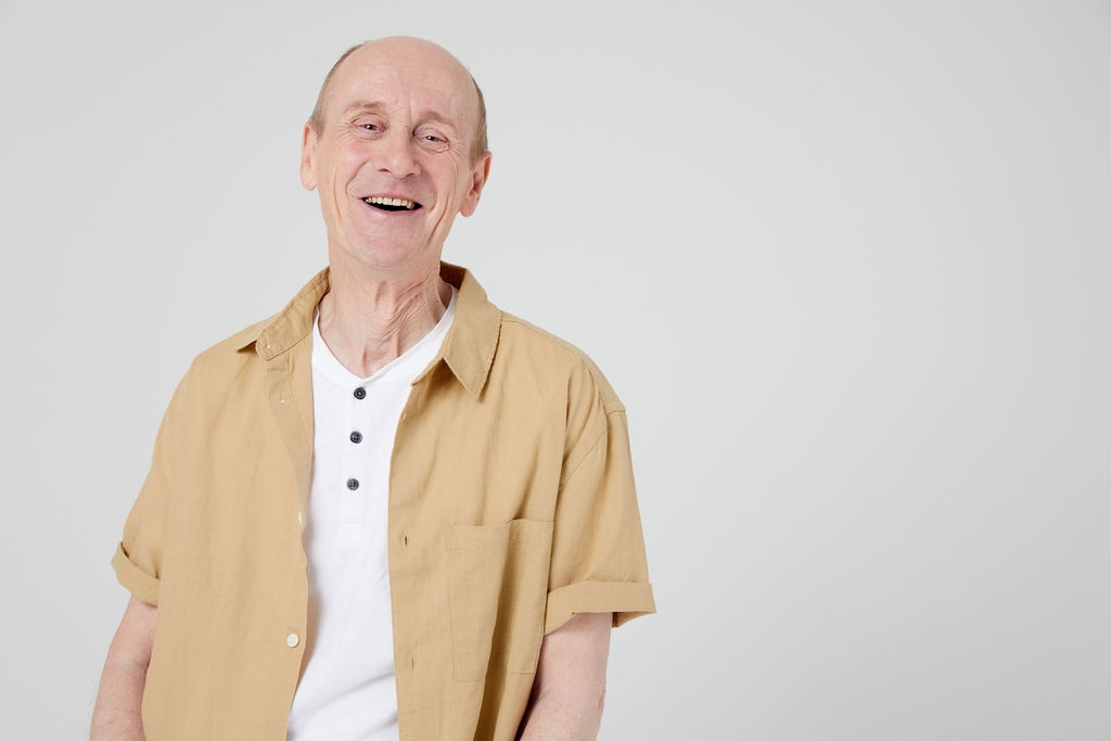 Man smiling in beige shirt with white top underneath Man smiling in beige shirt with white top underneath