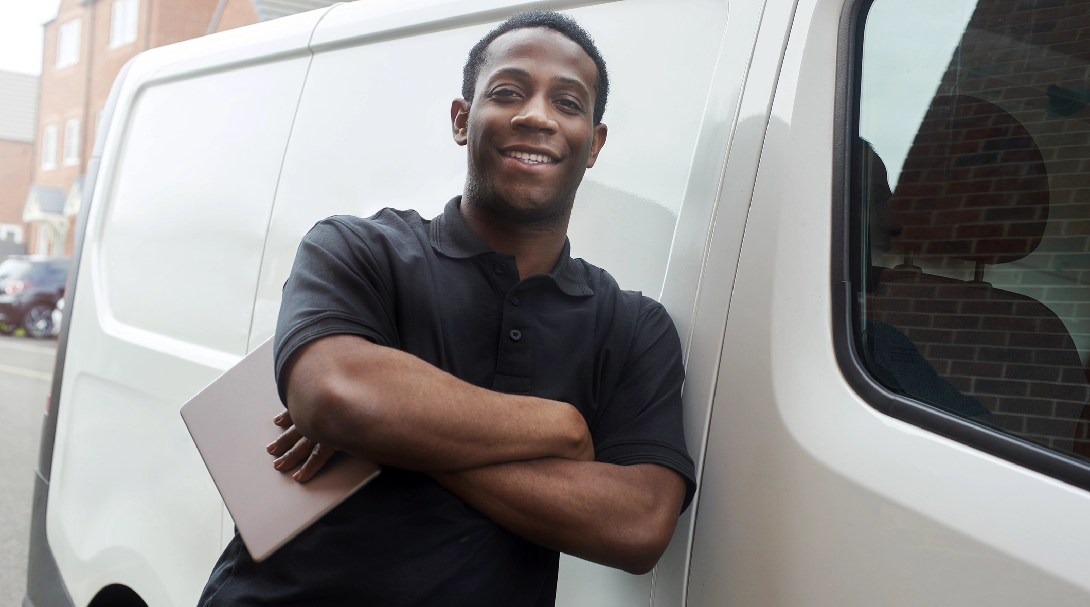 Smiling Engineer Leaning Against His Work Van With An Ipad In His Hand