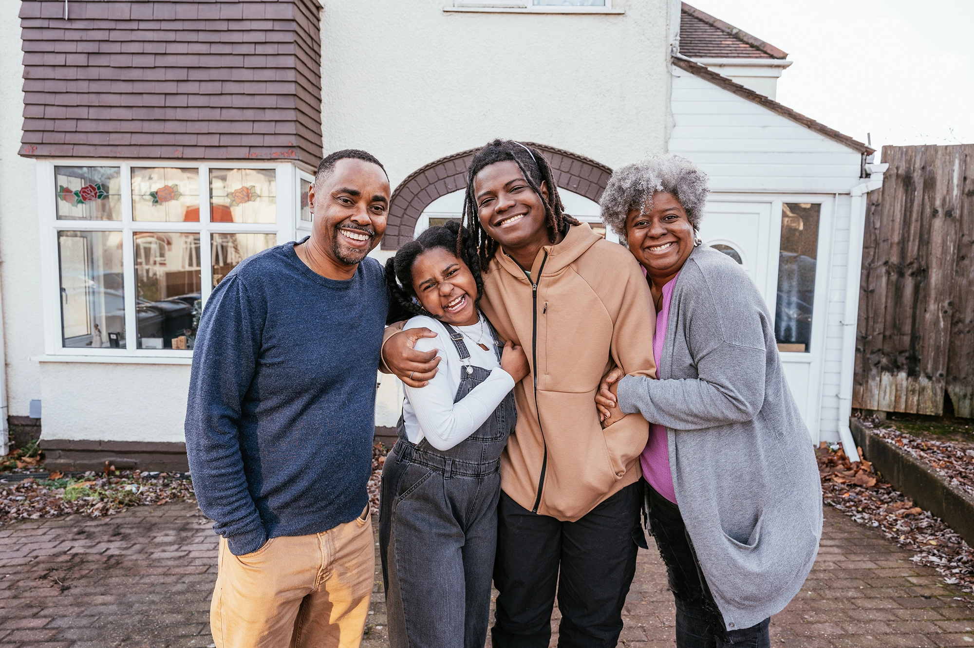 A Happy Family Standing Together In Front Of Their House