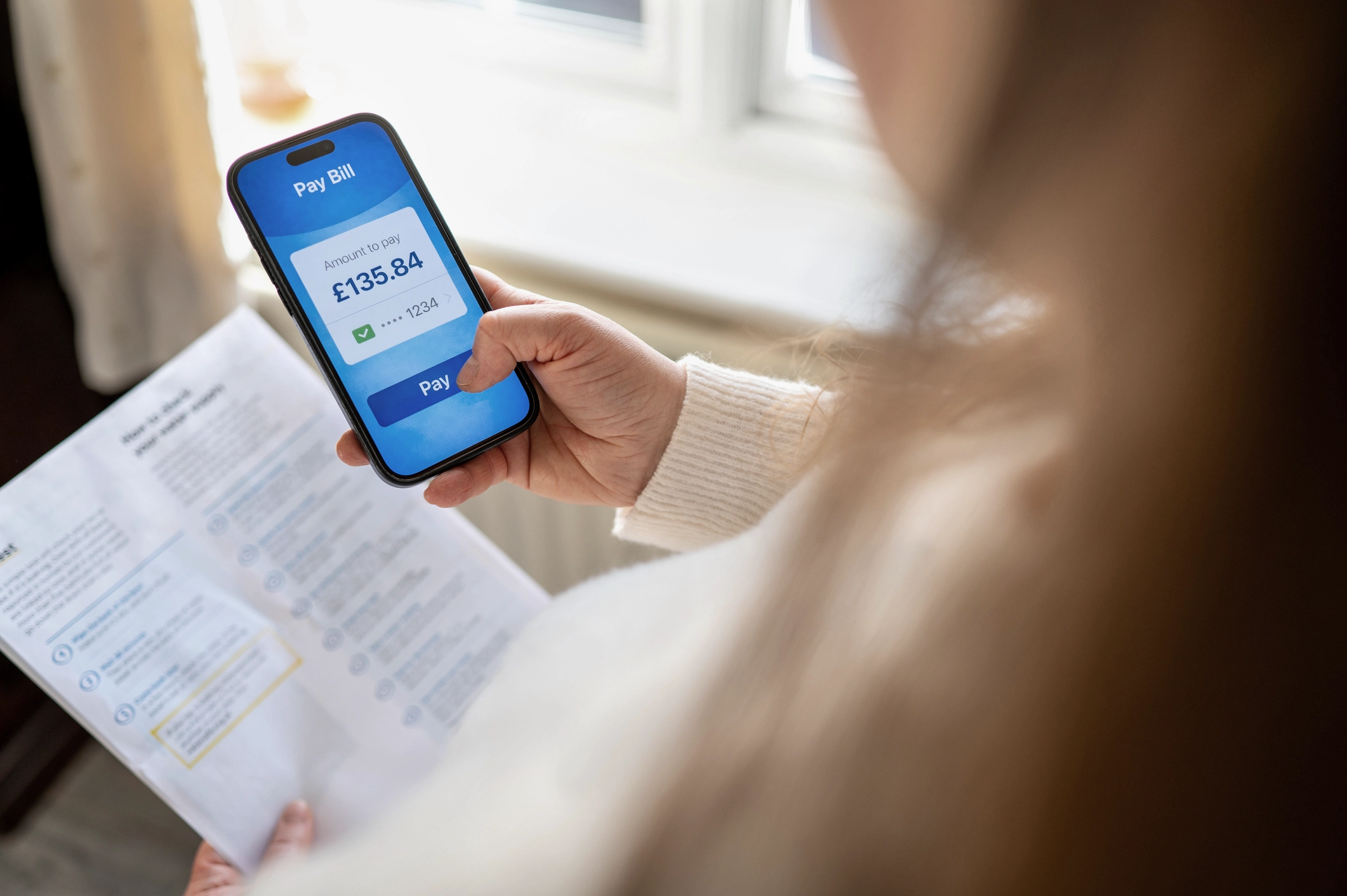 Woman Paying A Bill On A Mobile Phone Using A Banking App