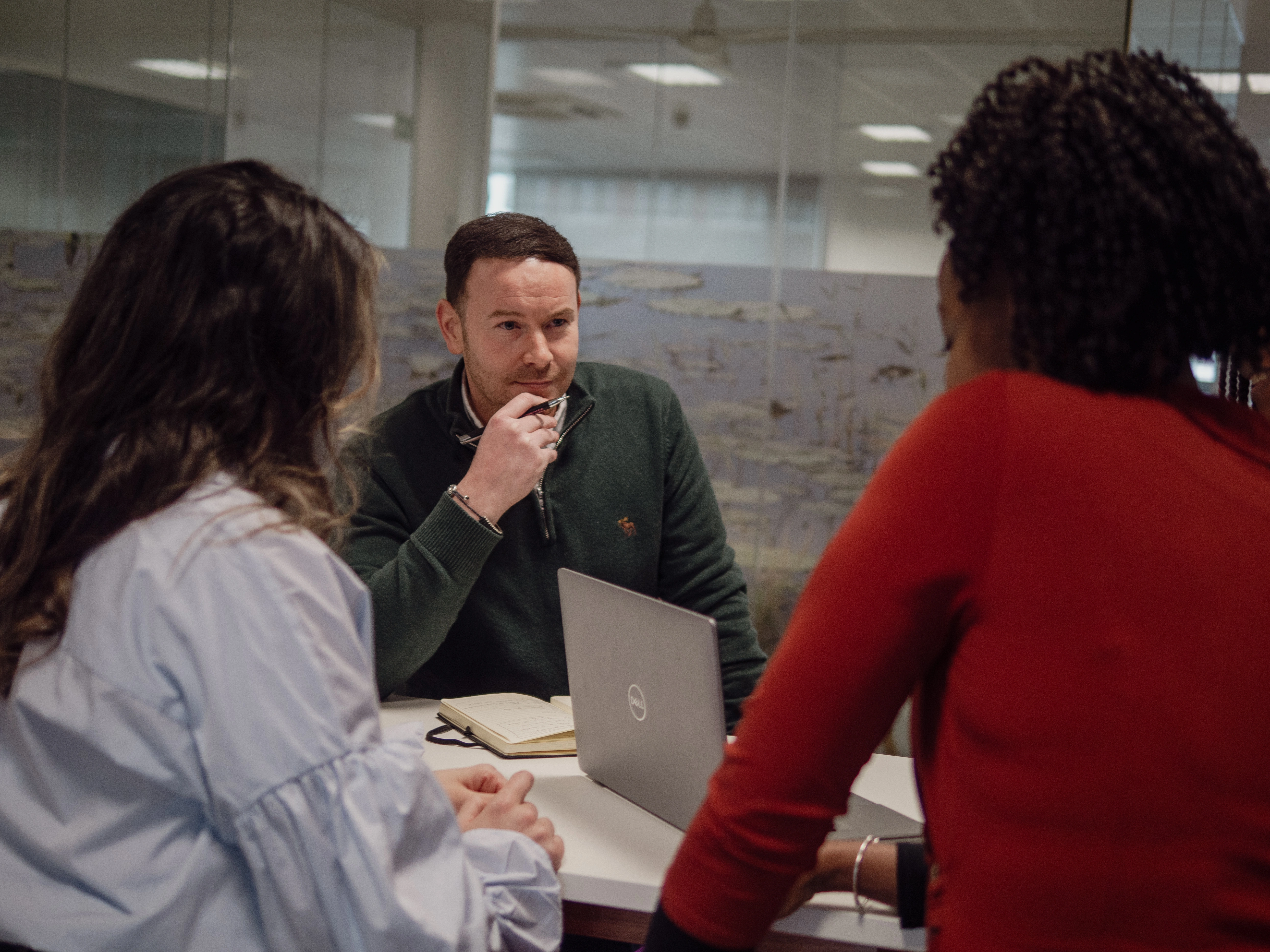 Three people are having a discussion in an office setting.
