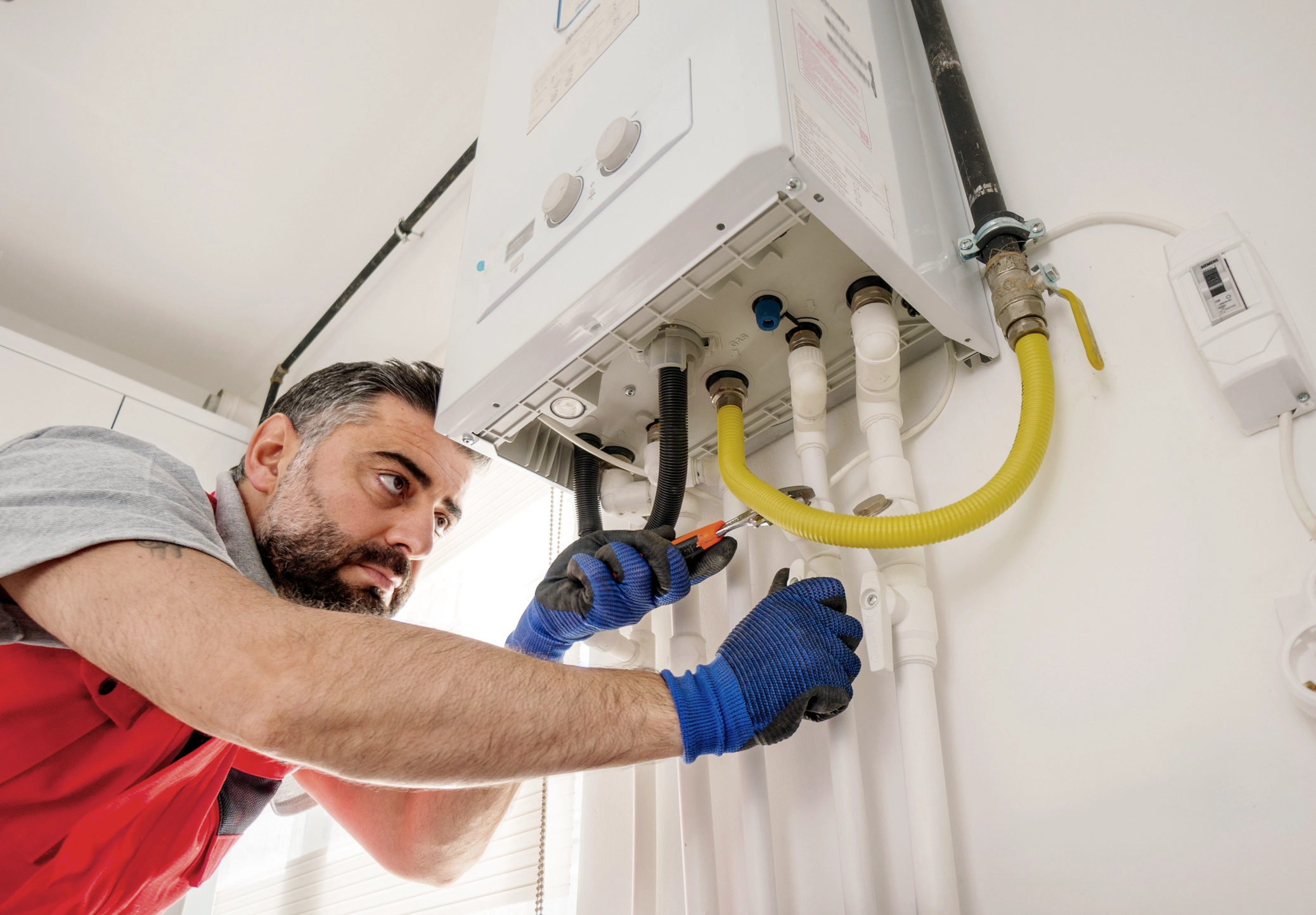 A boiler engineer servicing a boiler wearing blue gloves