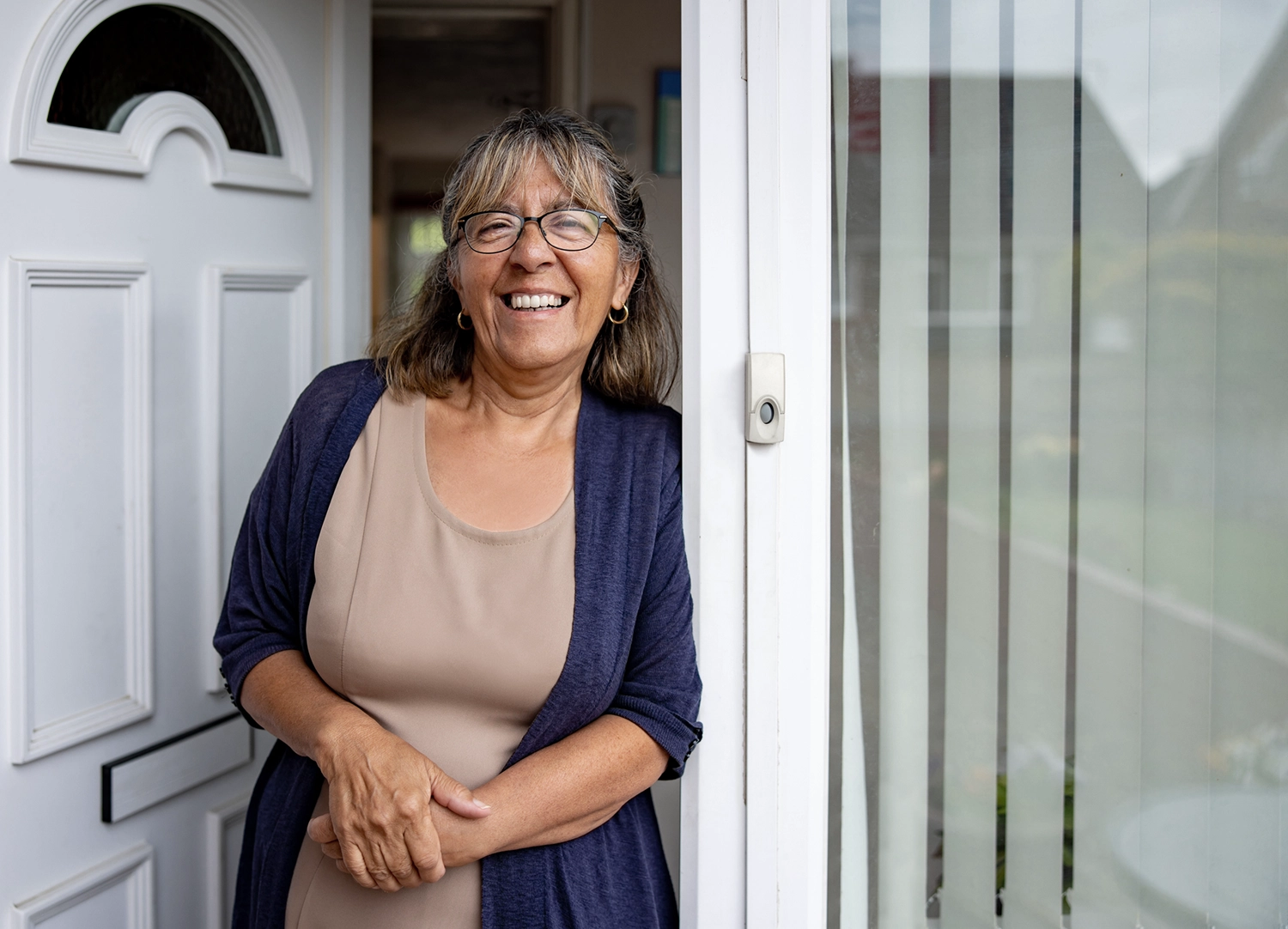 A Woman Smiling Standing Inside Her Open Front Door Looking Out