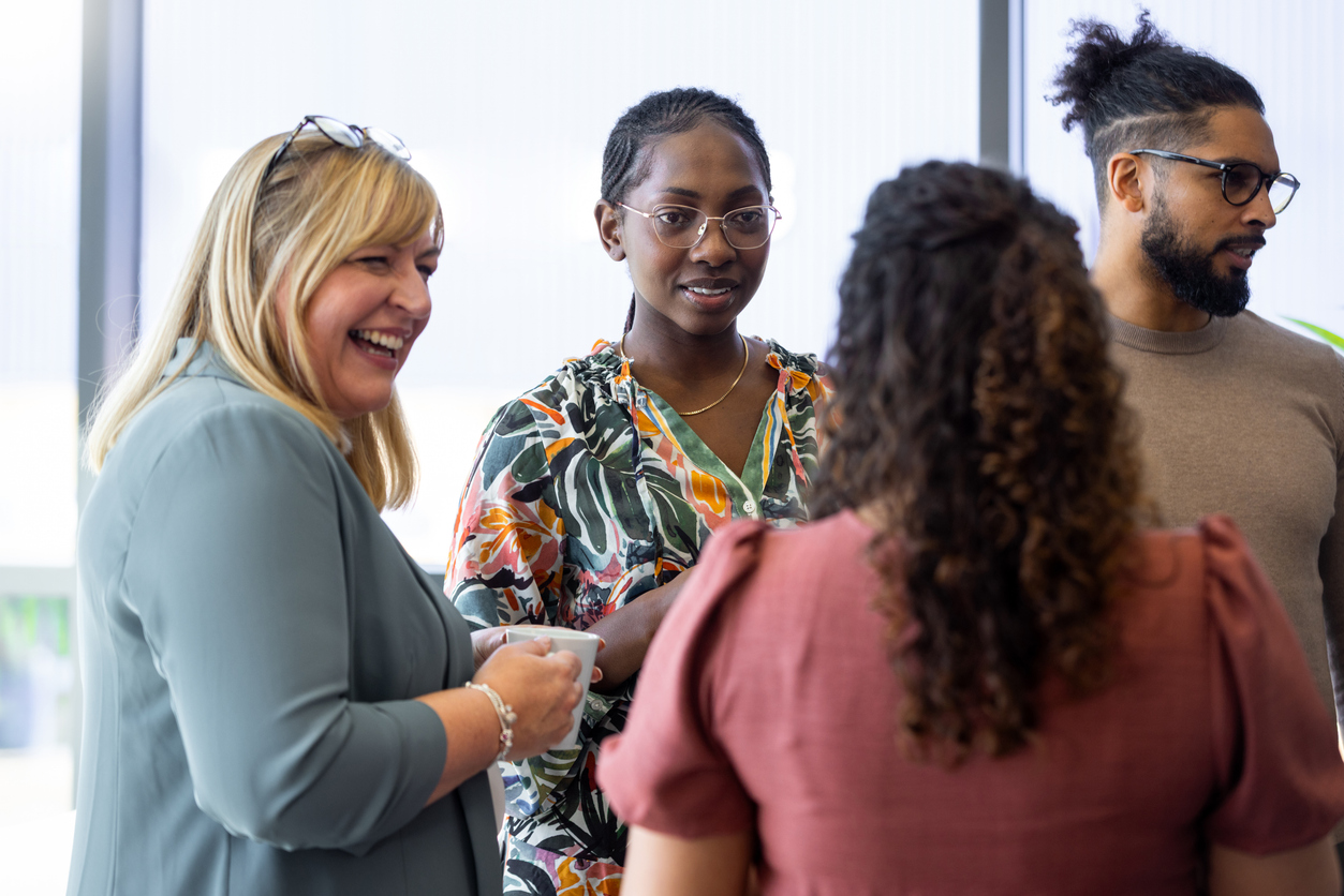 3 Women And A Man Talking In A Group And Smiling