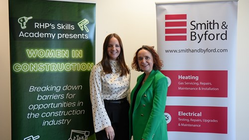 Two women standing and smiling between RHP and Smith & Byford banners