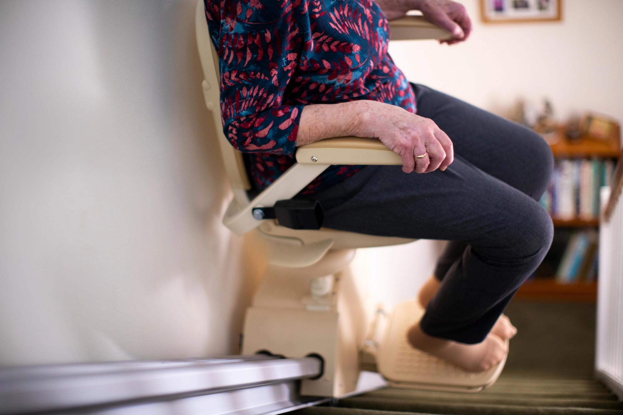 A woman sitting in a stair lift bare foot accessing her stairs