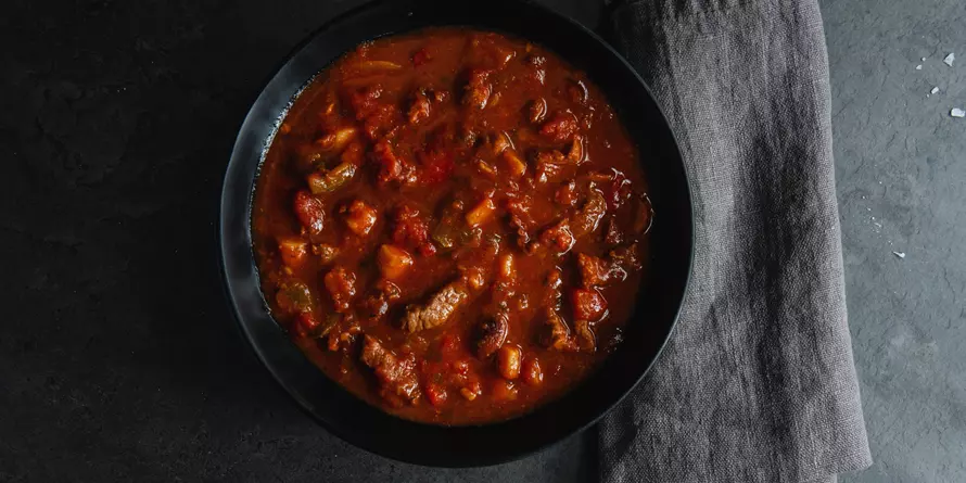 Gulasz Miesno Warzywny Podawany W Ciemnej Misce Na Szarym Tle Gulasz Miesno Warzywny Podawany W Ciemnej Misce Na Szarym Tle