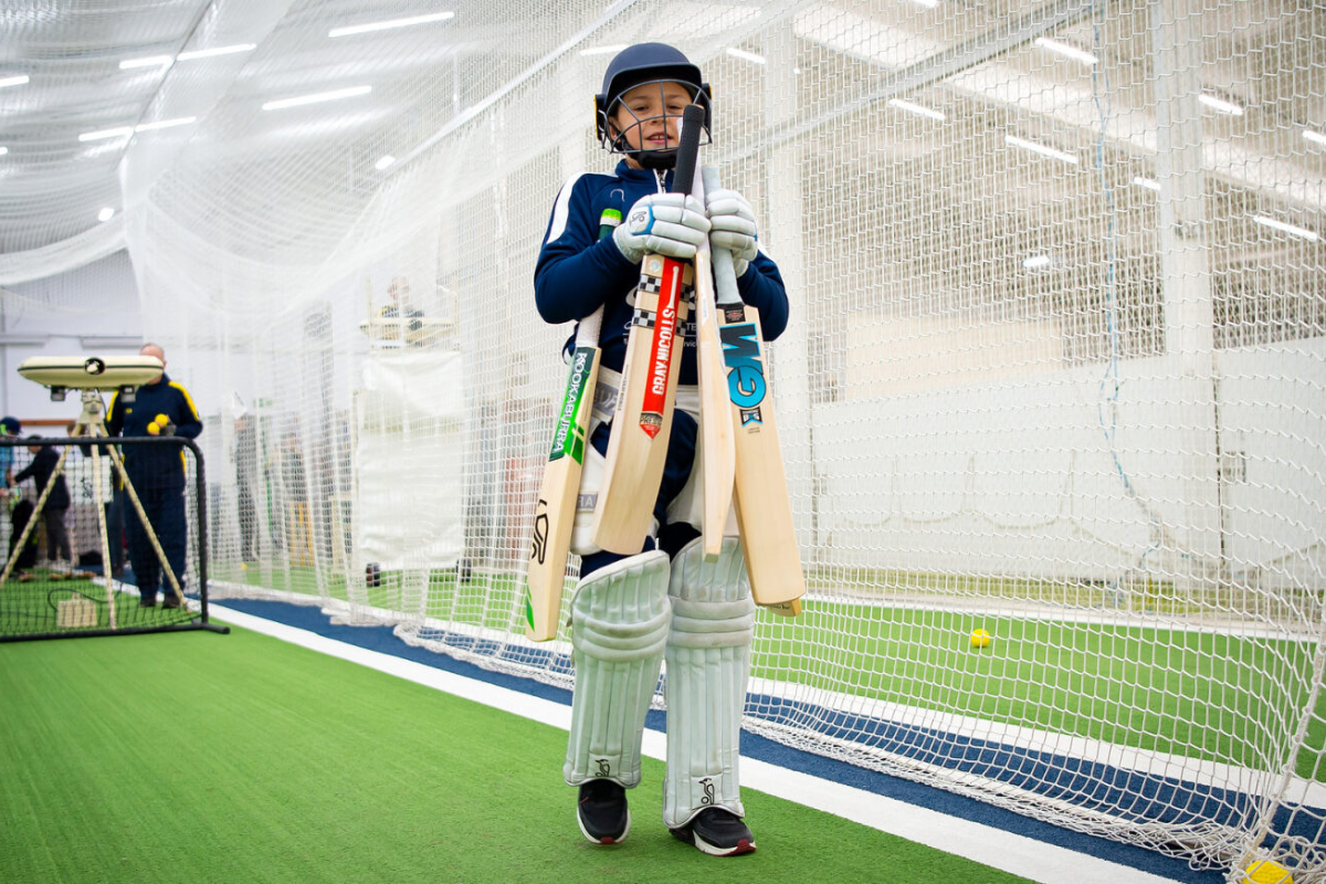 Young Cricketer carrying four cricket bats in the Serious Cricket net lanes at Dummer Cricket Centre