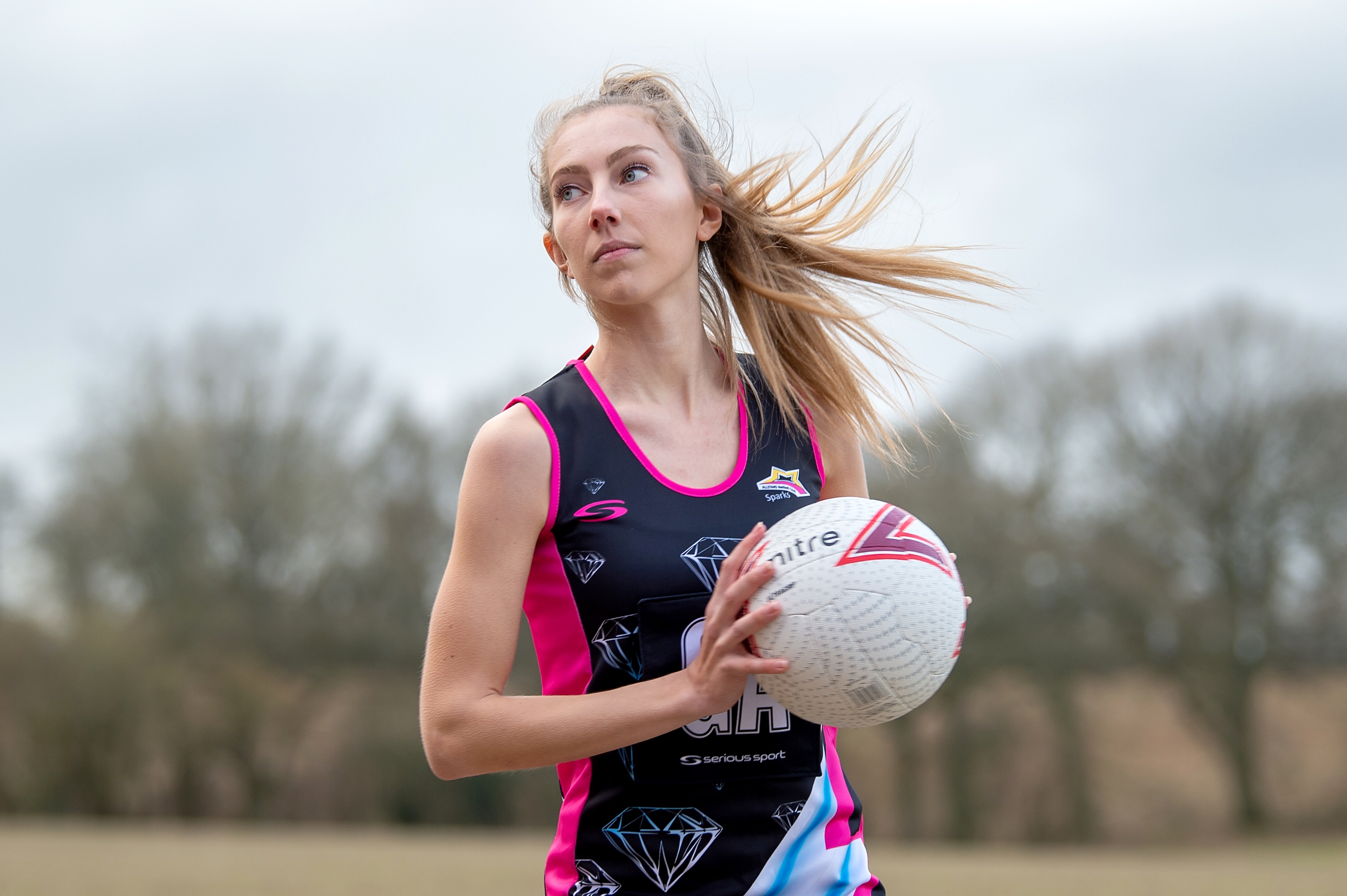Netball player preparing to pass the ball in a multi-coloured netball dress
