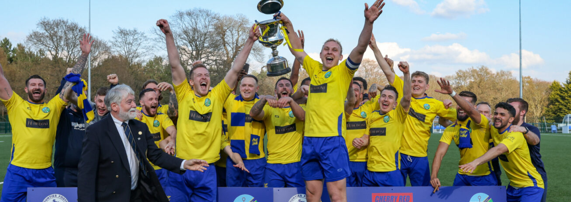 Team celebrating with a trophy in yellow Serious Sport kit 