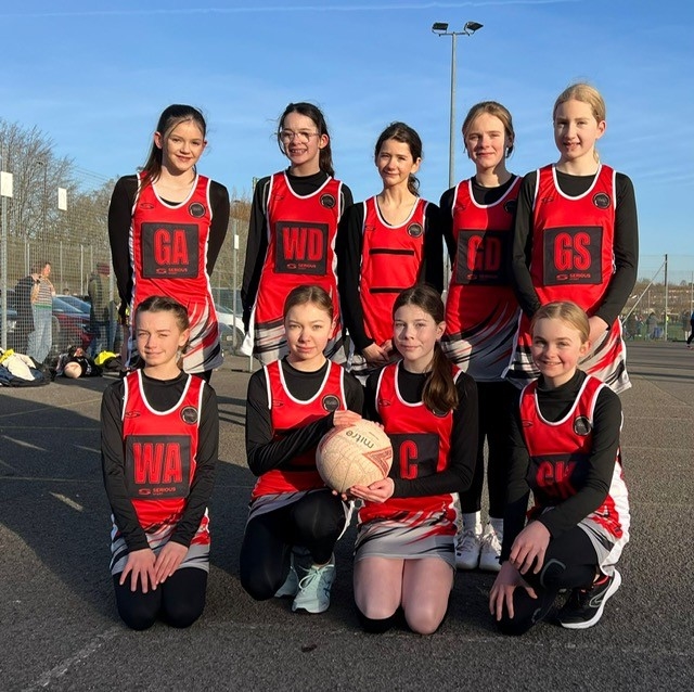 Aztec Netball team in a team photo in a red and black netball dress