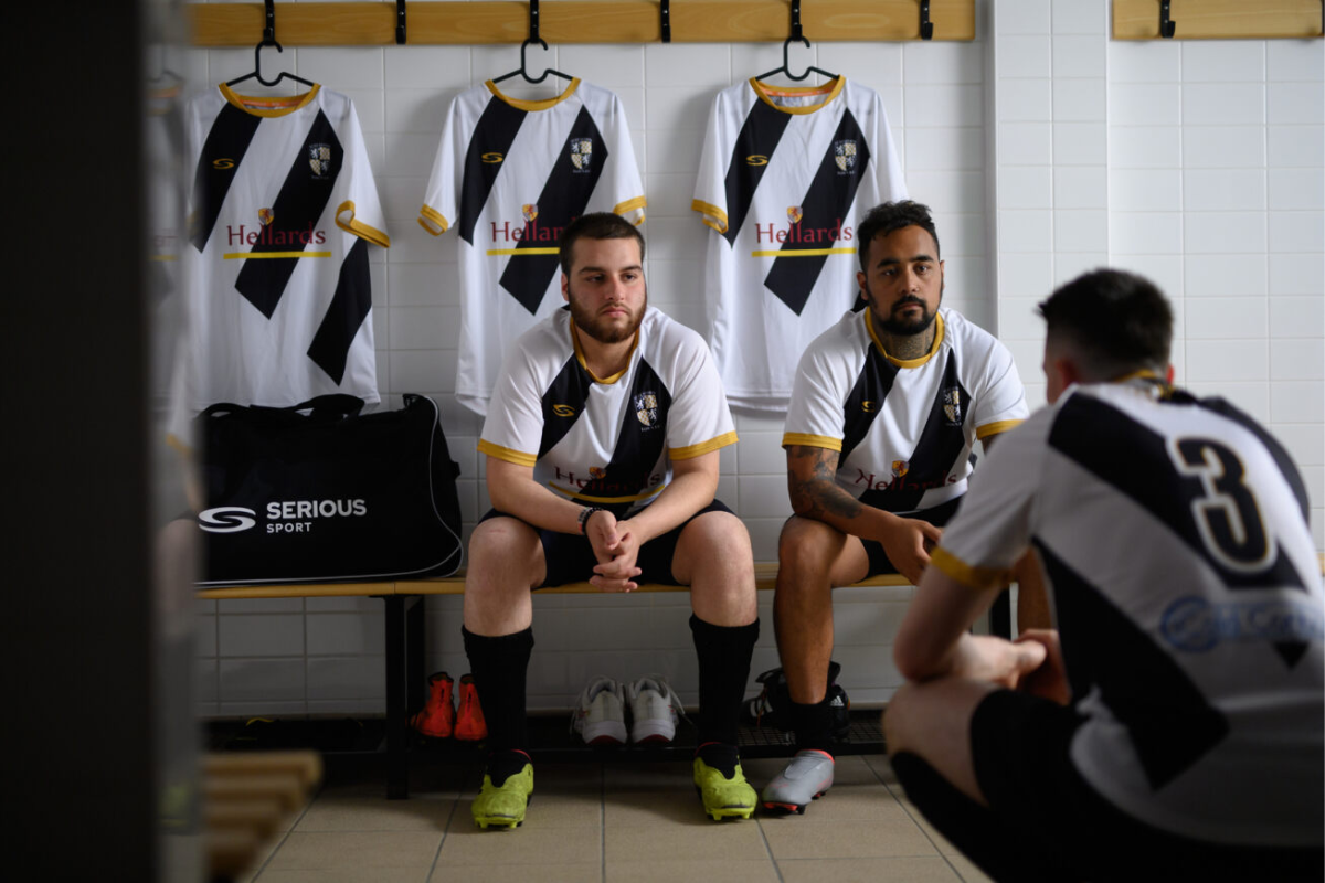 A team meeting in a sports changing room wearing black and white Serious Sport kit 