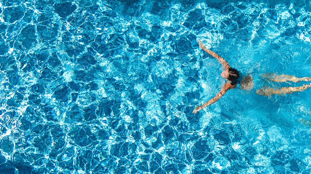 Woman swimming in an outdoor pool on a sunny day