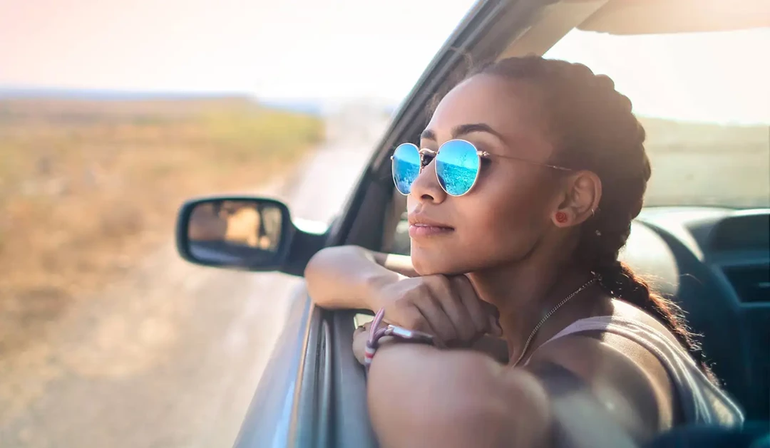 Woman in the countryside in summer, leaning out of her car window