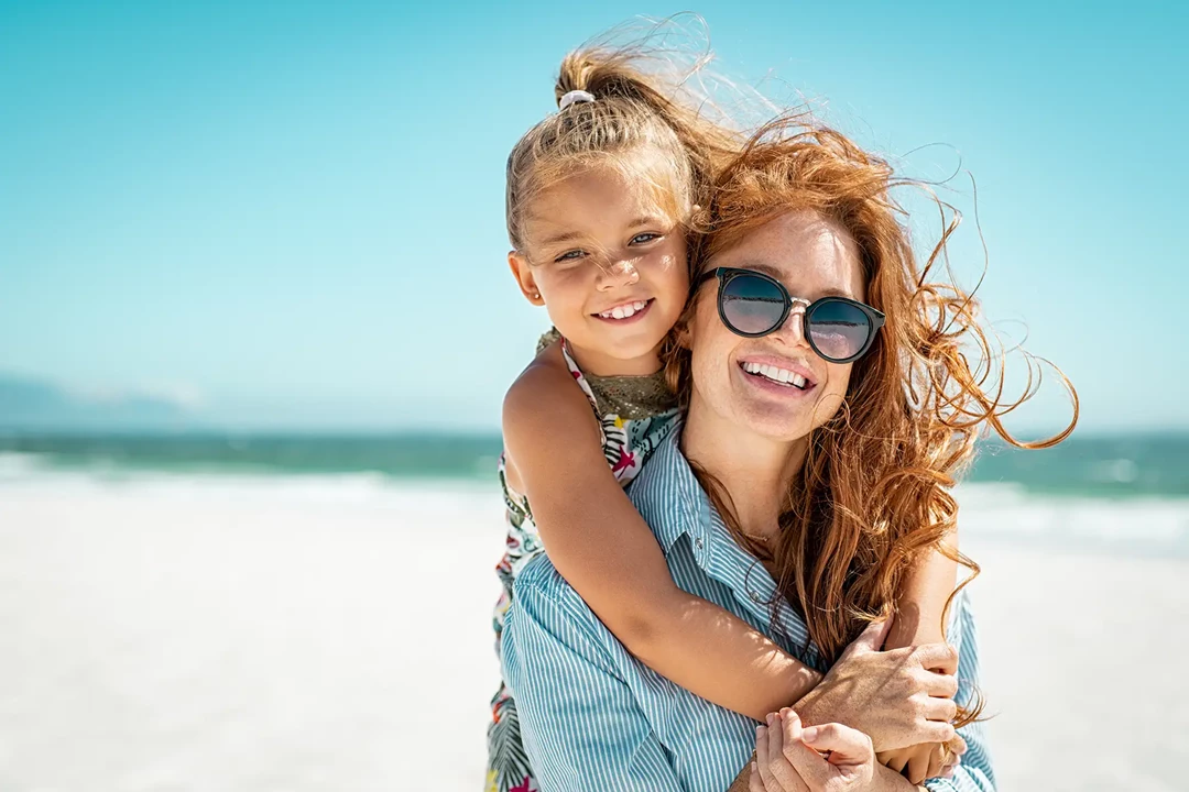 Mother carrying her daughter on the beach