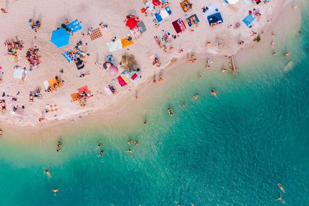 Aerial view over a beach on a sunny day with lots of sunbathers
