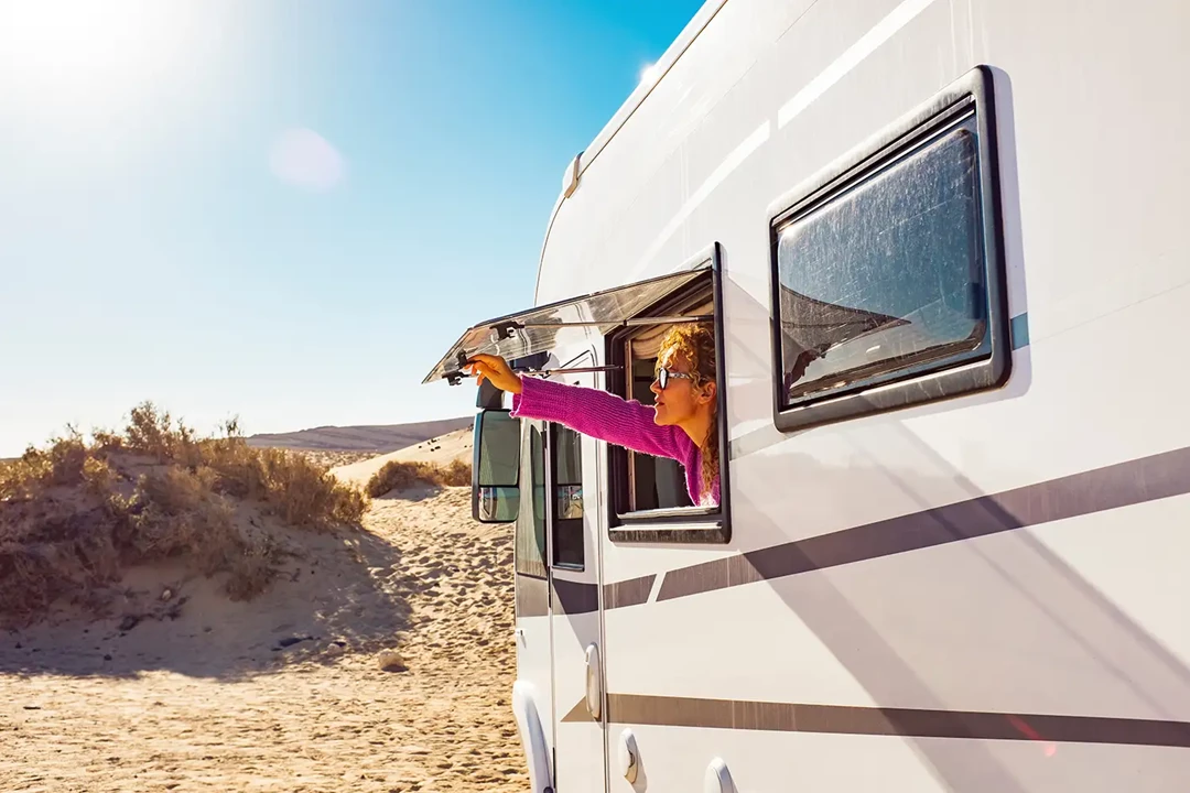 Open window with woman looking out of caravan.