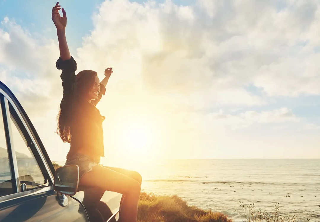 Woman celebrating near the sea at sunset.