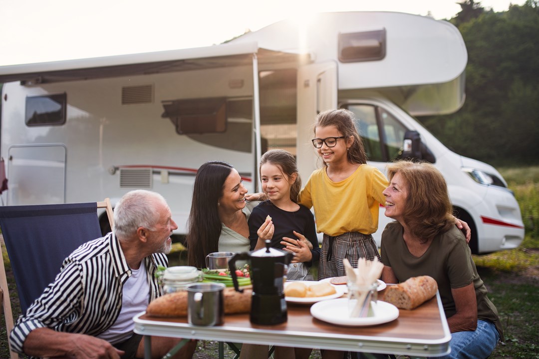Family meal with campervan behind them