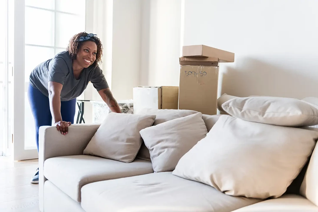 Woman next to her sofa at home