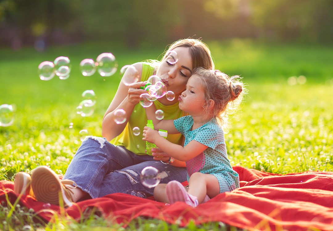 mother and daughter on picnic blanket on a sunny afternoon.