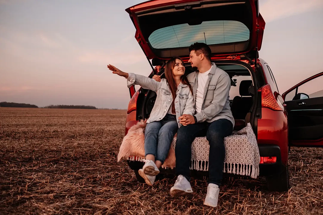 Couple sitting in the boot of their car in the outback