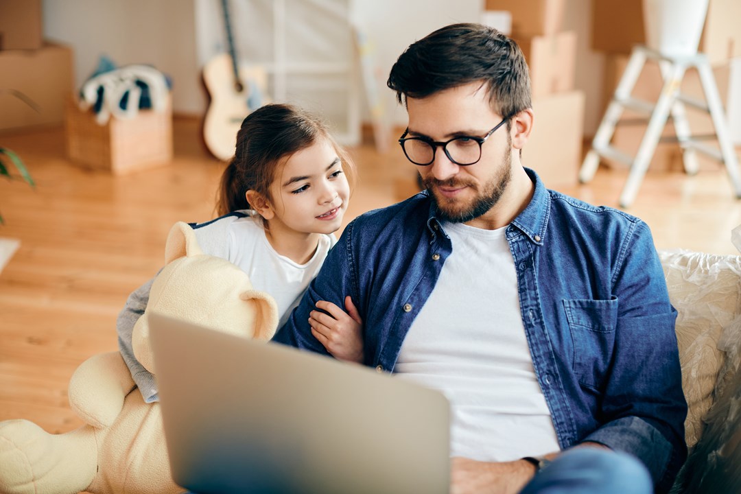 Man with daughter looking at laptop in living room