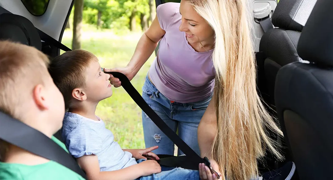 Woman strapping her children into the car