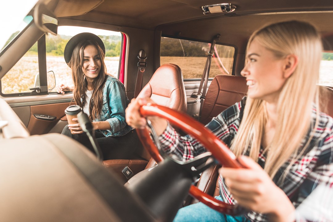 Two young female friends driving