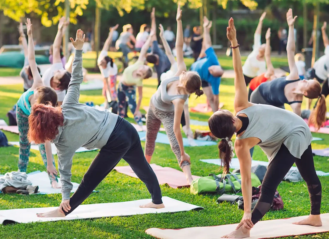 Group of people exercising on mats outside in the park