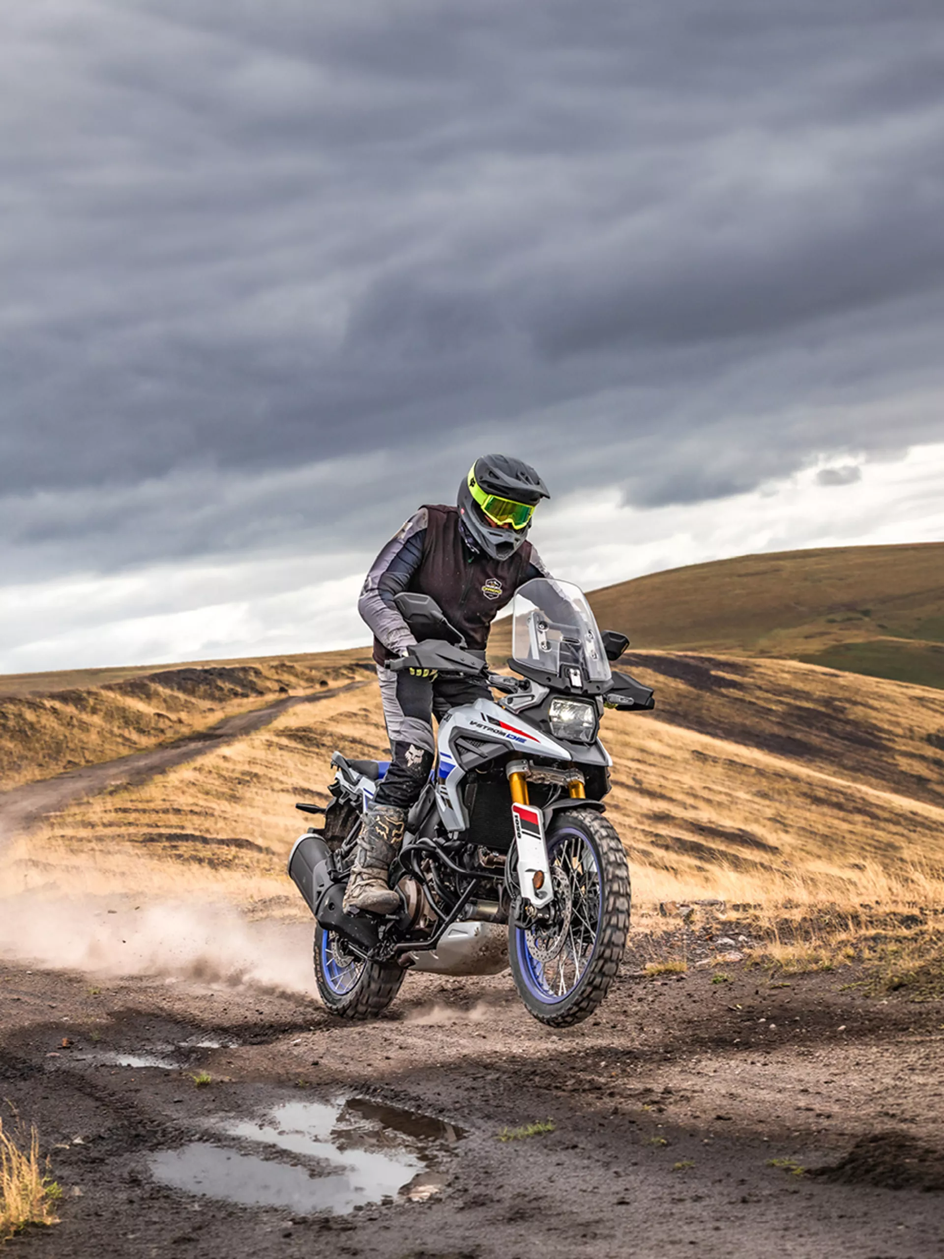 Suzuki V-Strom 1050DE with the ride up on the footpegs on a desert trail
