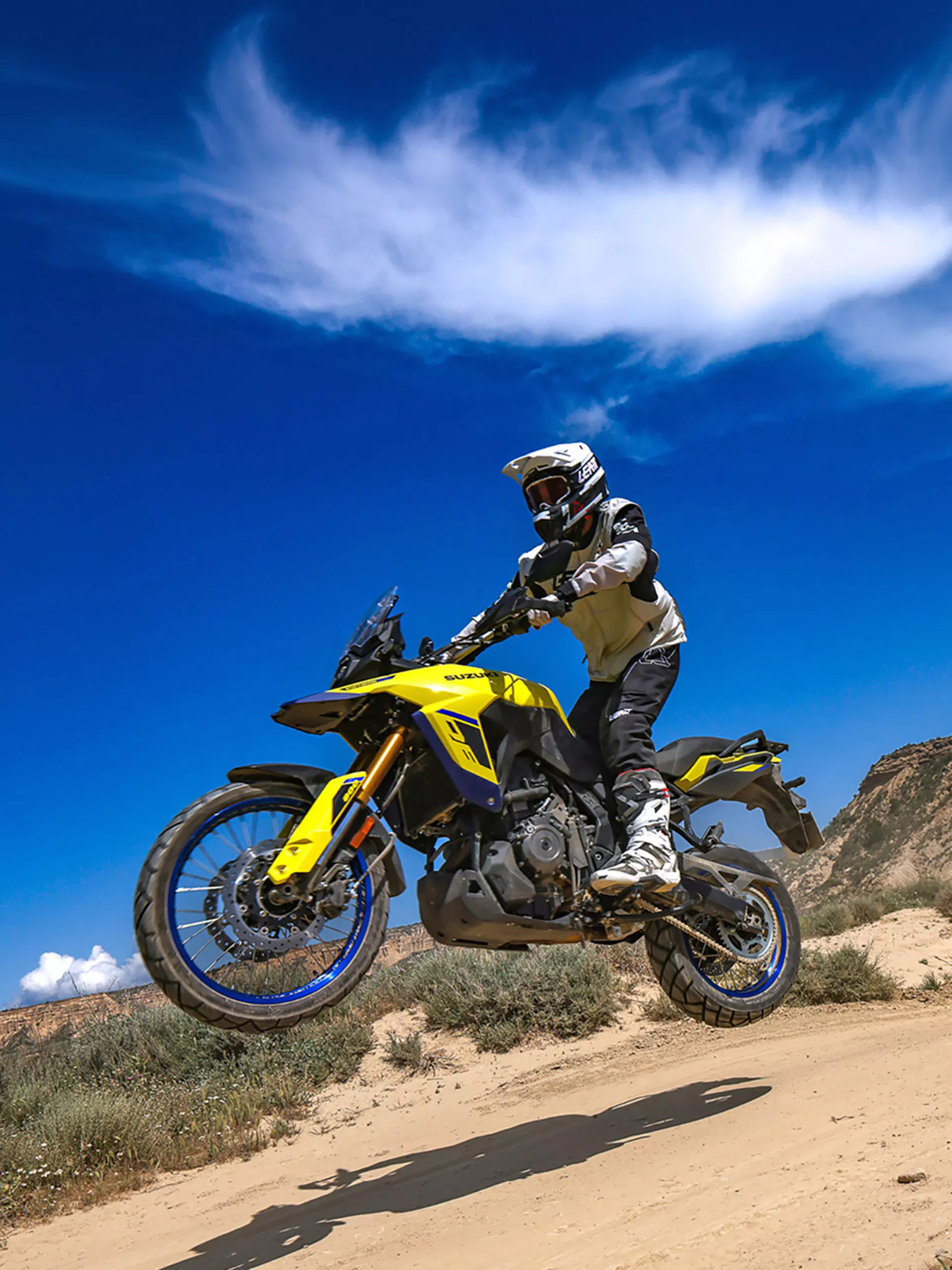 Suzuki V-Strom 800DE in the air on a desert trail hill