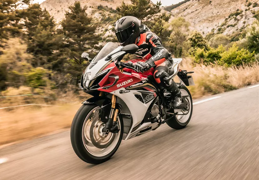 Suzuki GSX-R1000R riding hard along a mountain road.