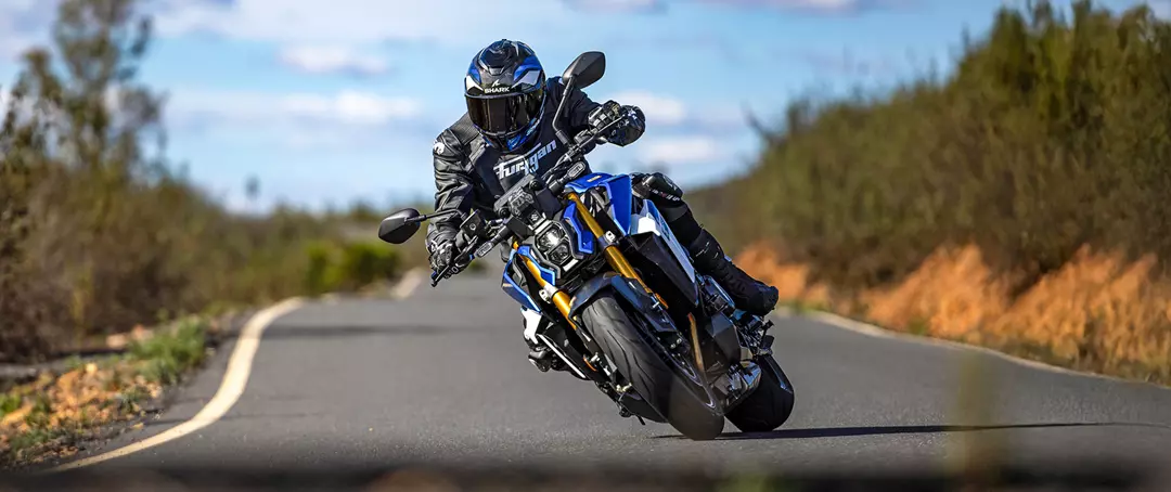 Suzuki GSX-S1000 leaning hard into a corner on a country road.