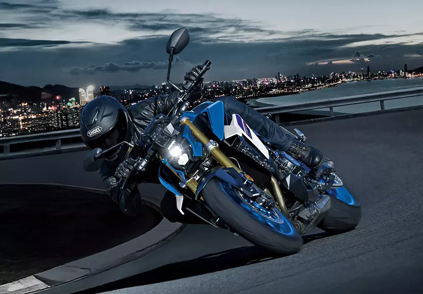 Suzuki GSX-S1000 slightly leaning into a corner at night on the outskirts of a city