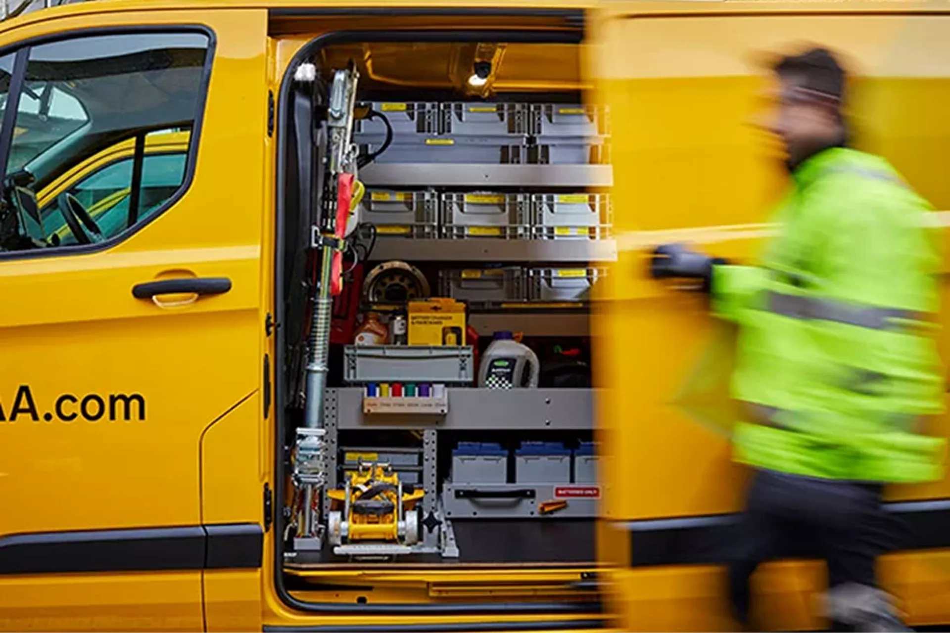 Roadside assistance technician beside a yellow breakdown recovery van