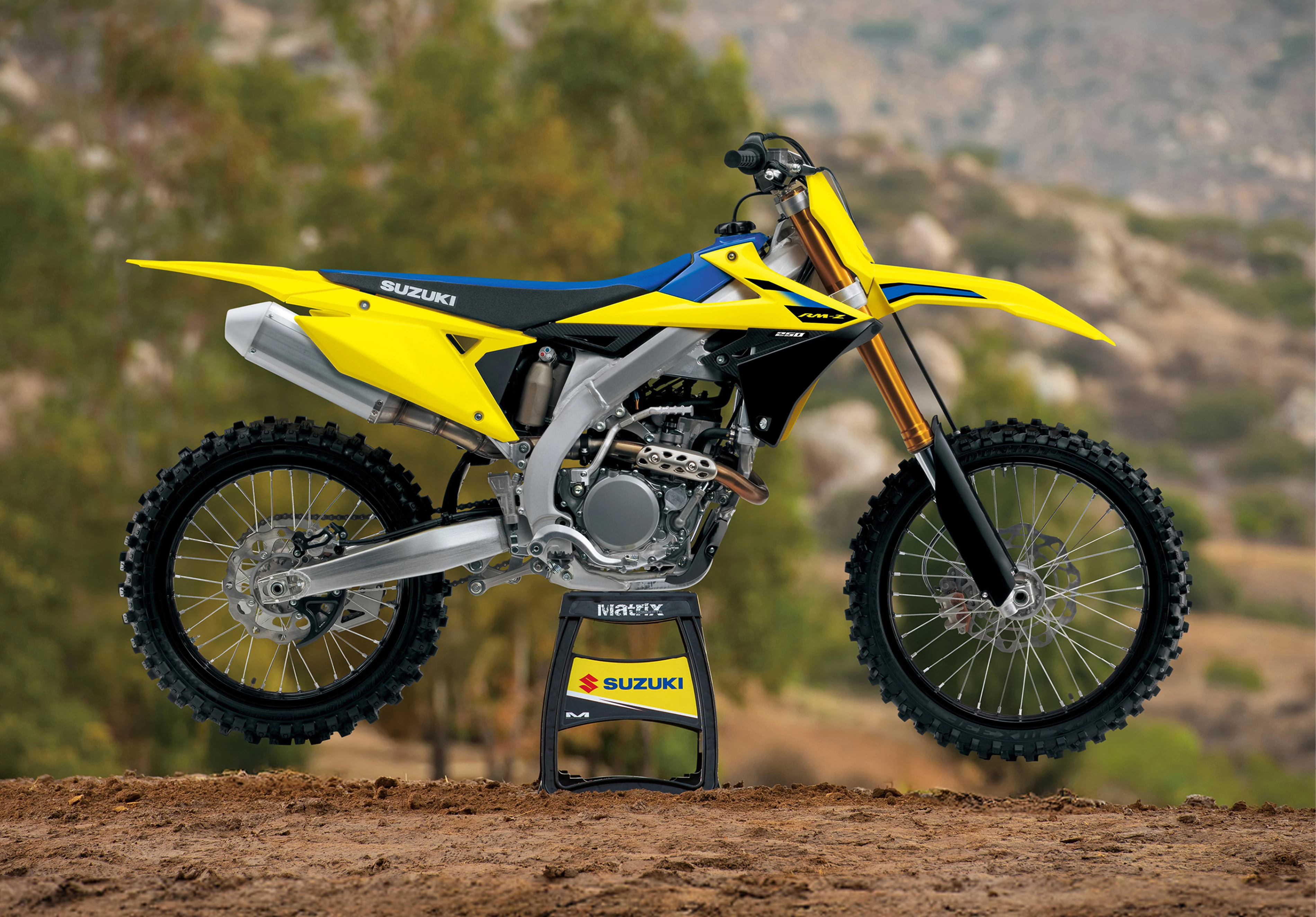 Suzuki RM-Z250 on a stand with mountains in the background