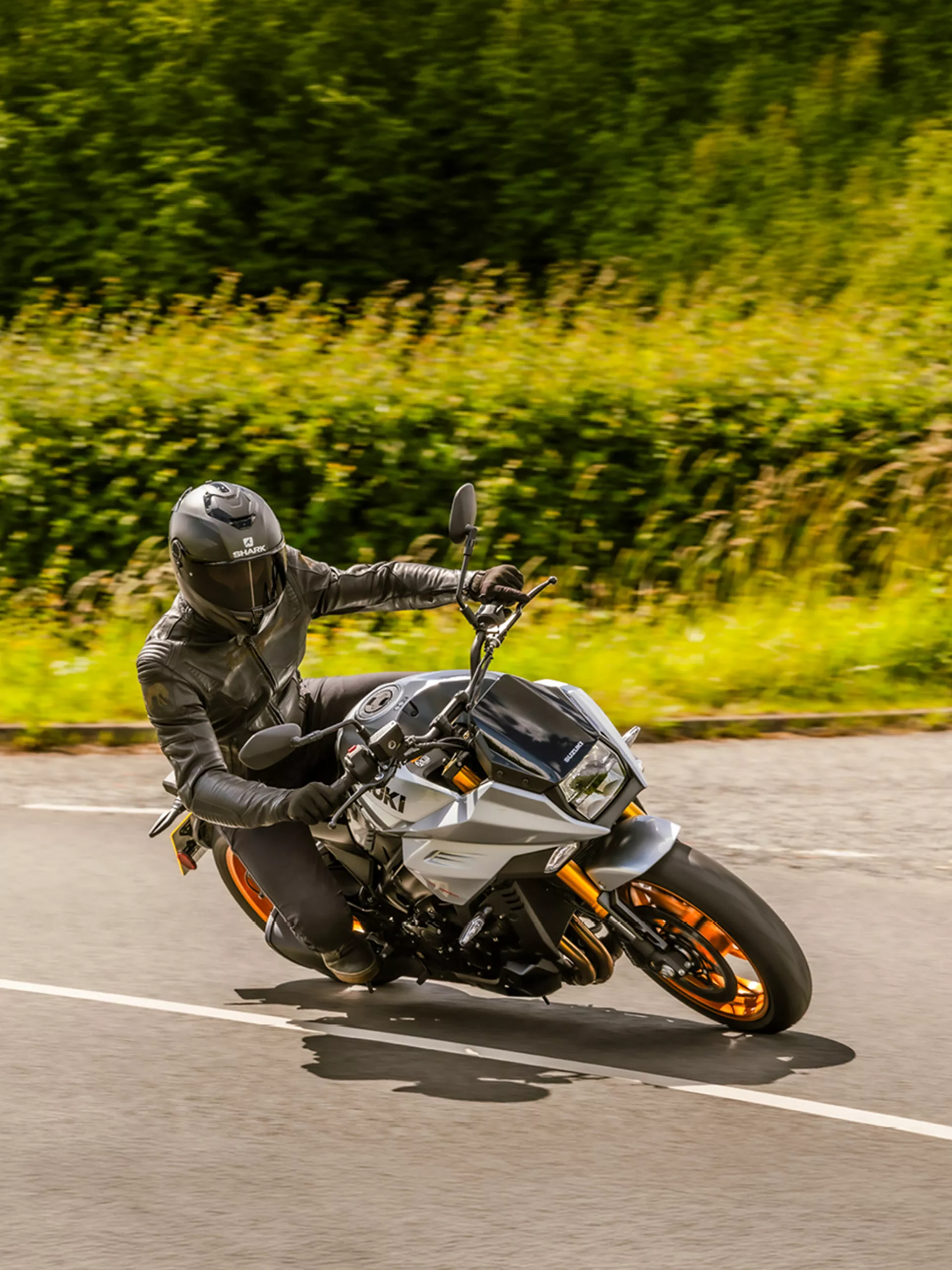 Suzuki Katana leaning hard into a corner with a countryside landscape behind.