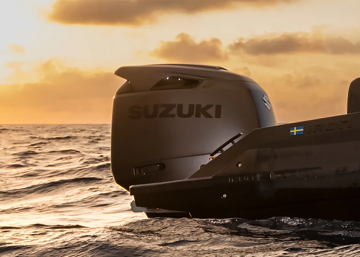 Suzuki DF250AUNX KURO outboard set against a sunset sky