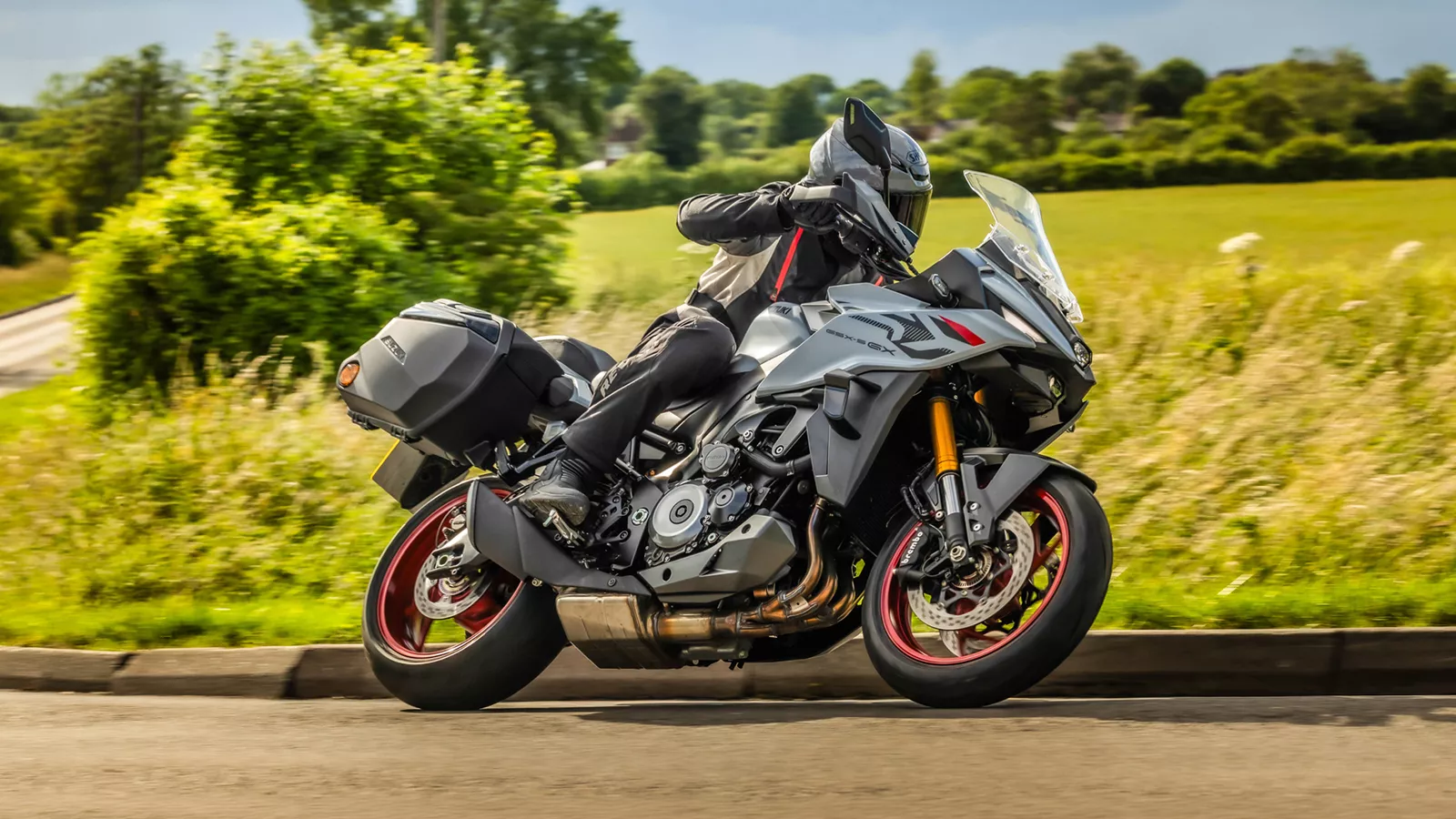 Suzuki GSX-S1000GX+ leaning into a corner with a field behind
