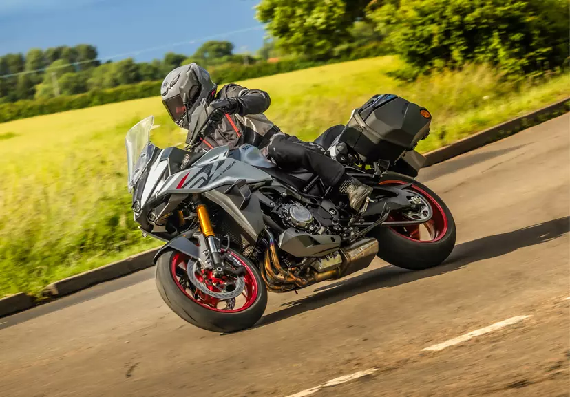 Suzuki GSX-S1000GX+ pushing hard into a corner with a field behind.