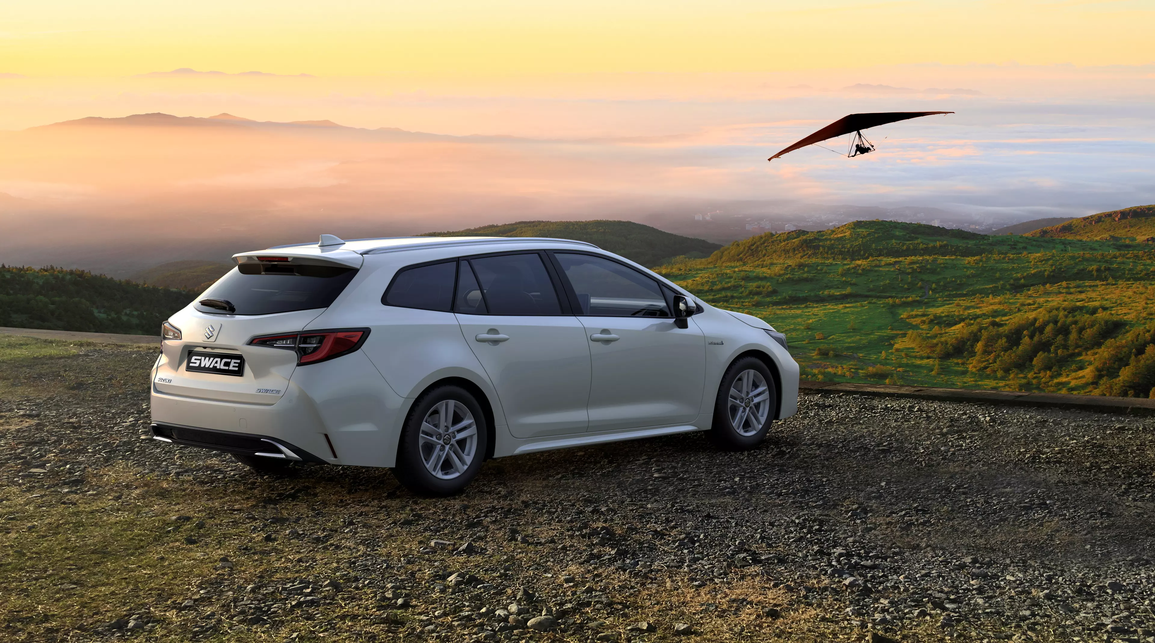 Super white Suzuki Swace parked on a scenic country road at sunset with a paraglider soars peacefully in the air.