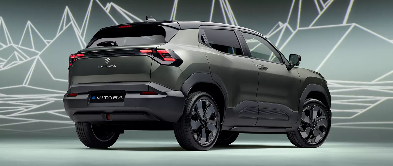 Rear view of the Suzuki e Vitara in Land Breeze Green Pearl Metallic, showcasing modern LED tail lights and alloy wheels