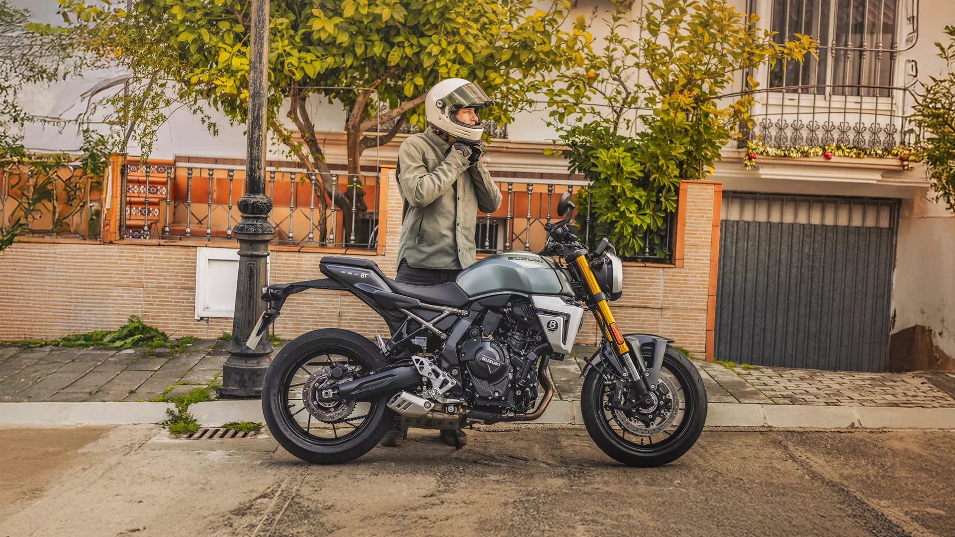 Suzuki GSX-8T right hand side static with rider taking off helmet behind. 