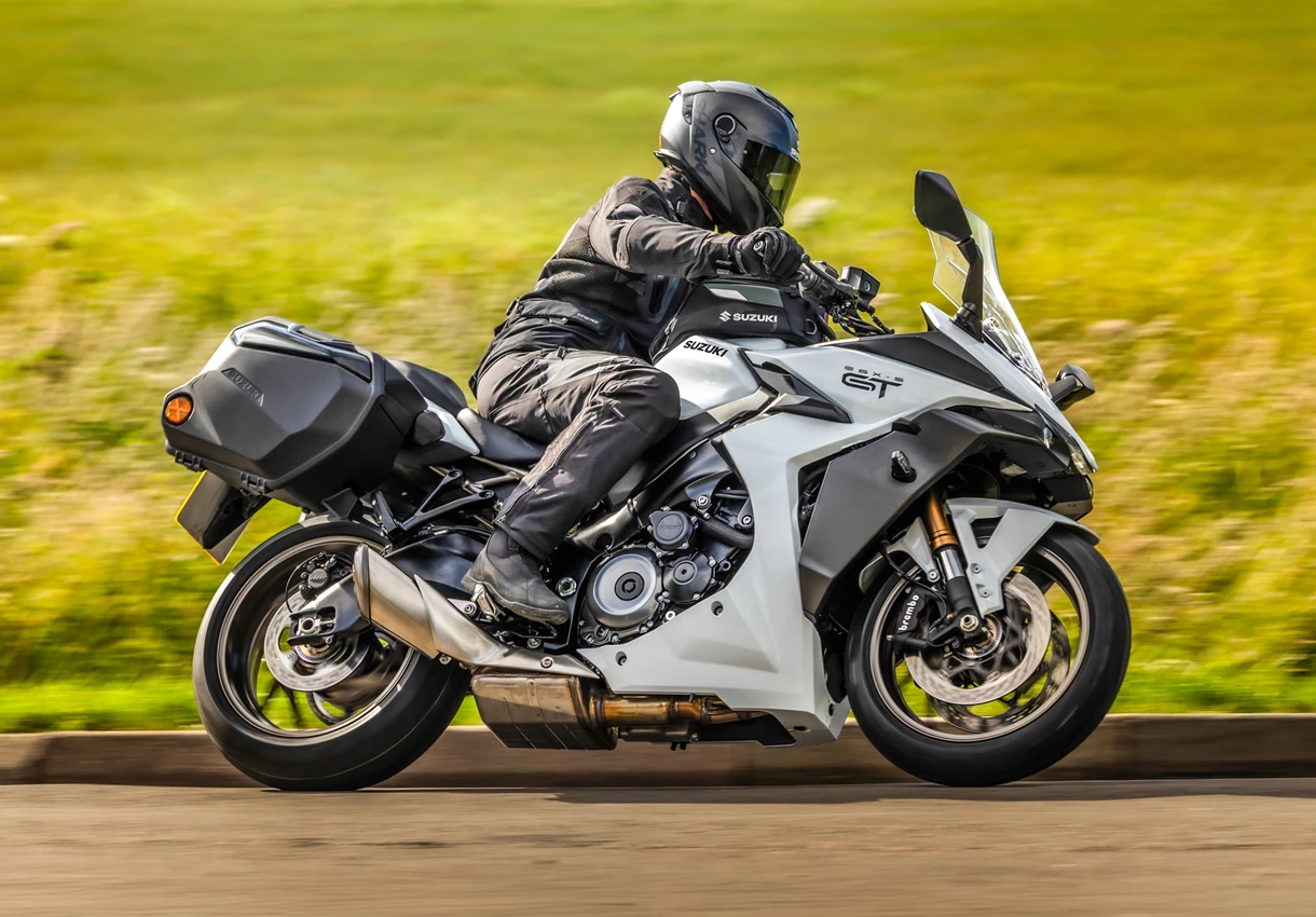 Suzuki GSX-S1000GT+ leaning into a corner on a country road.