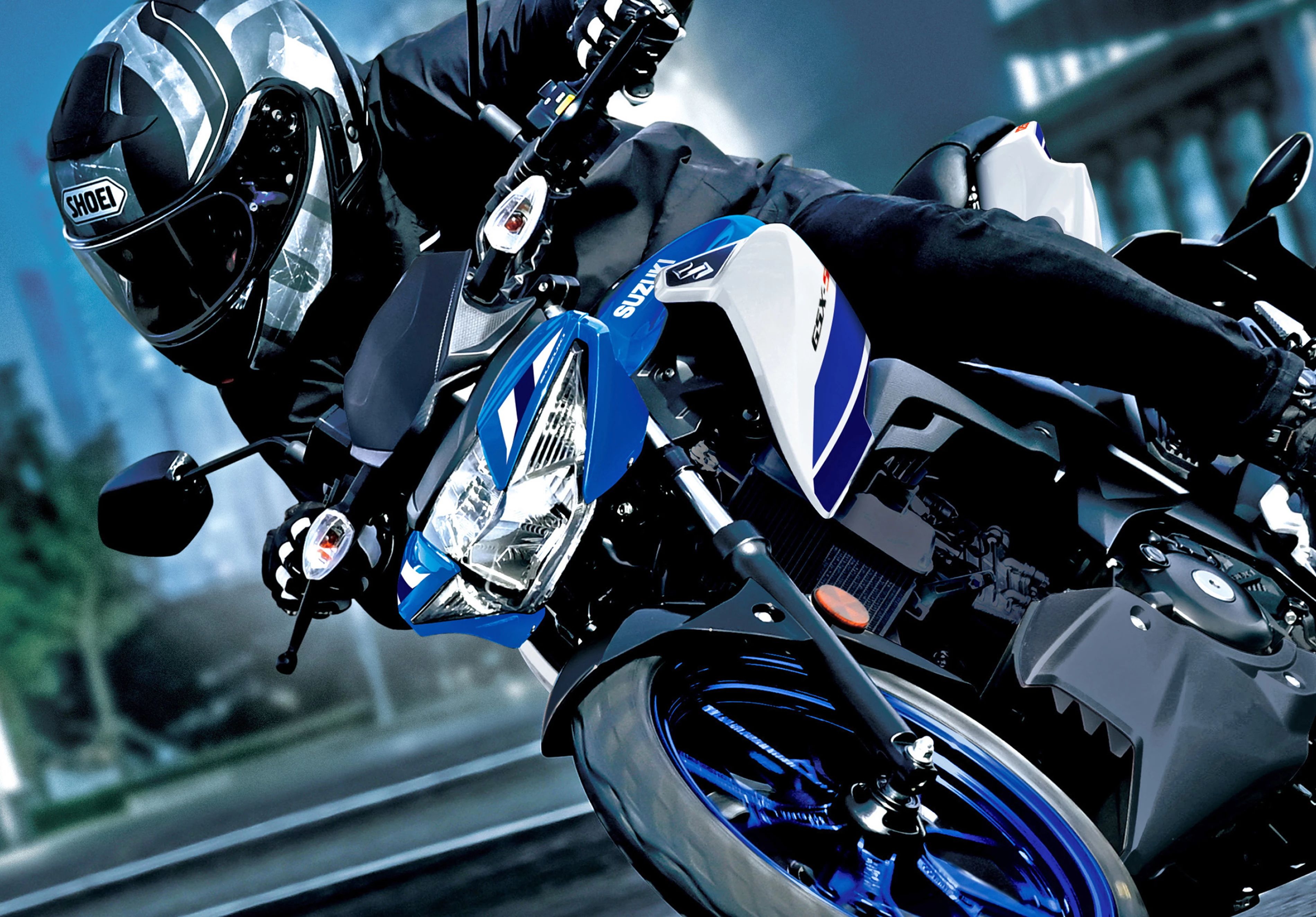 Suzuki GSX-S125 at night leaning into a corner with a city background, close up.