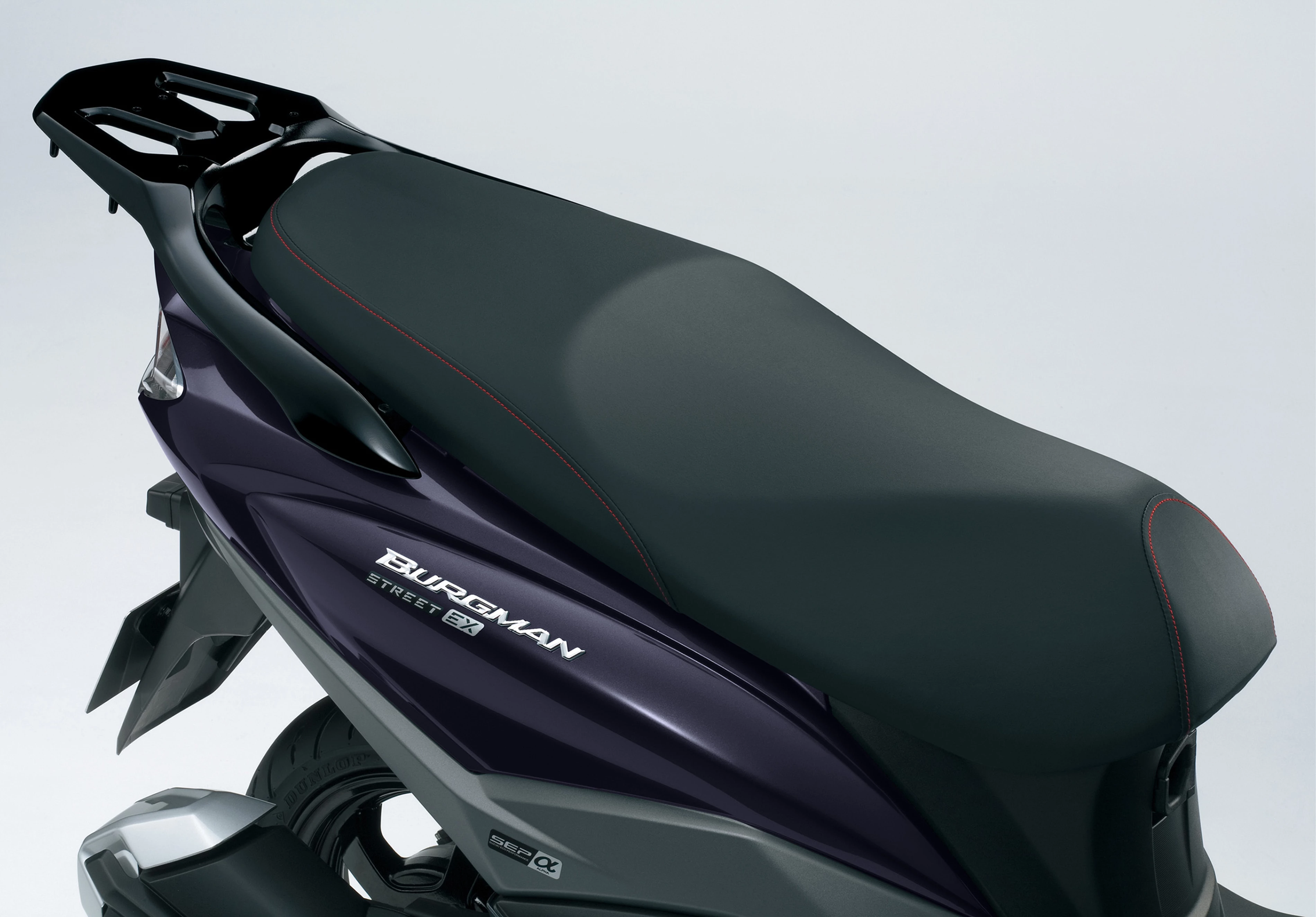 Suzuki Burgman Street 125EX side profile, focusing on the seat design and embossed Burgman branding against the metallic body.