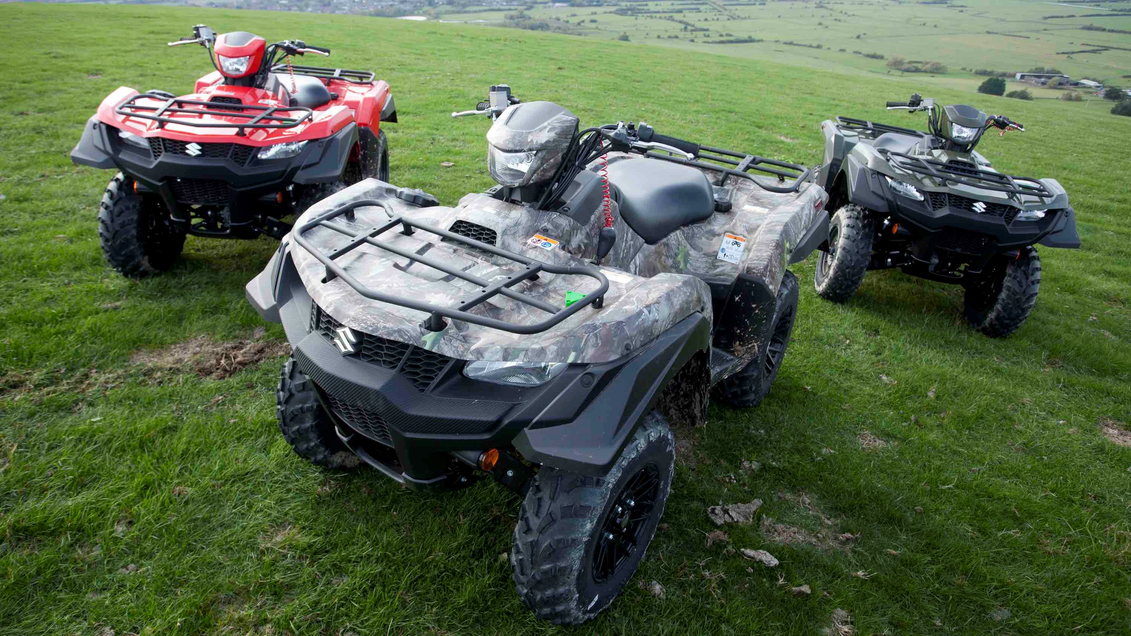 Trio of Suzuki ATVs in a field