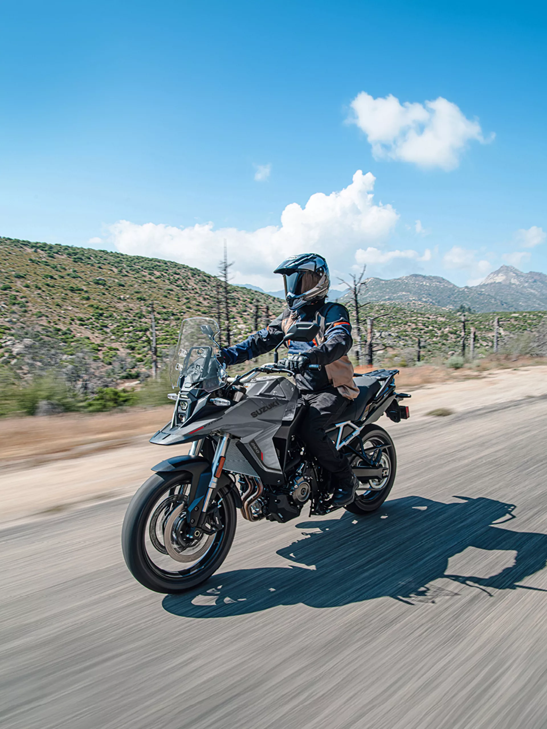 Suzuki V-Strom 800RE riding along a mountain lined road.