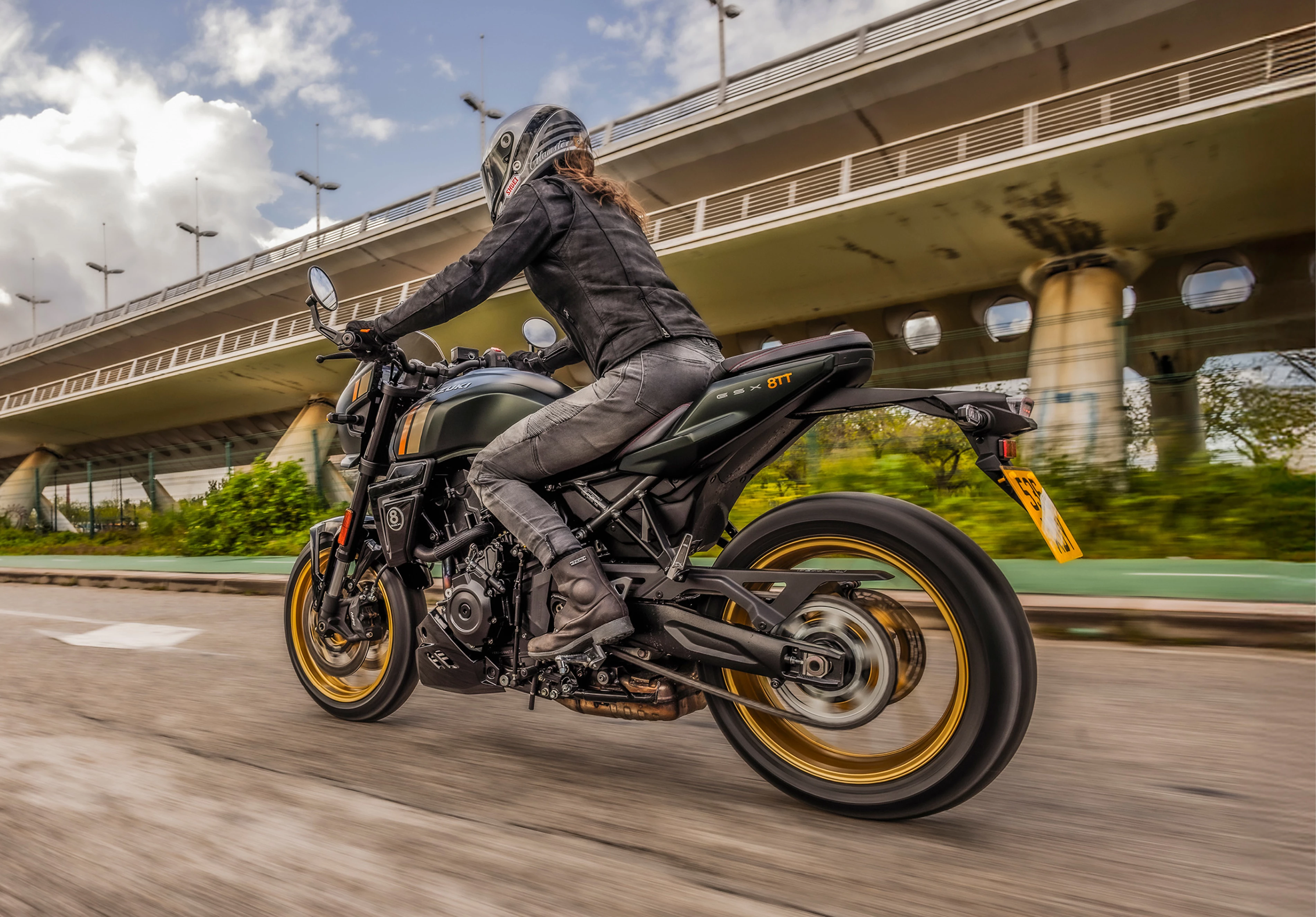 Suzuki GSX-8TT riding through the outskirts of a city with a bridge behind